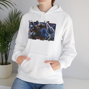 May include: White hooded sweatshirt with a front pocket. The graphic on the front features a muscular figure with lightning bolts against a dark background. The sweatshirt is made of a soft material.