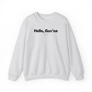 Può includere: Felpa grigio chiaro con la scritta "Hello, Guv'na" in nero, con testo aggiuntivo sottostante. La felpa ha girocollo, maniche lunghe e un motivo maculato.
