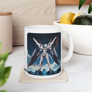Puede incluir: Taza de cerámica blanca con una ilustración detallada de un robot futurista con armadura blanca, roja y negra, sobre un cielo azul y un paisaje. El robot tiene grandes alas y está de pie sobre una plataforma. La taza tiene un asa curva.