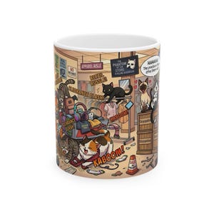 Könnte beinhalten: Ein weißer Keramikbecher mit einer farbenfrohen Cartoon-Illustration von Katzen, die in einem Einzelhandelsgeschäft für Chaos sorgen. Das Design enthält Texte wie Apparel Aisle, Retail Russle, Clearance Clash, Kaboom und The Phantom of the Store.