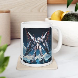 Puede incluir: Taza de cerámica blanca con una ilustración detallada de una guerrera futurista con grandes estructuras en forma de alas. La obra de arte utiliza blanco, rojo y azul sobre un fondo oscuro. La taza tiene un asa estándar y un acabado brillante.