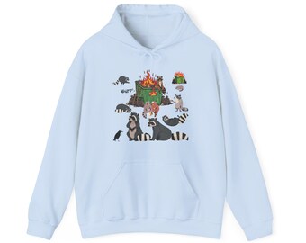 Puede incluir: Sudadera con capucha azul claro con una ilustración caprichosa de mapaches reunidos alrededor de una hoguera. El diseño incluye un cuervo y la palabra "WHAT?!" en un bocadillo. La sudadera tiene un bolsillo de canguro y una capucha con cordón.