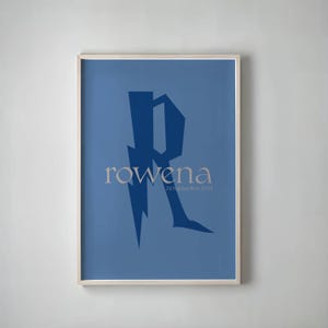 May include: A framed poster with a blue background features a stylized letter "R" in a darker blue, with the name "rowena" in a light beige font. Below the name is the date "24 September 2024".