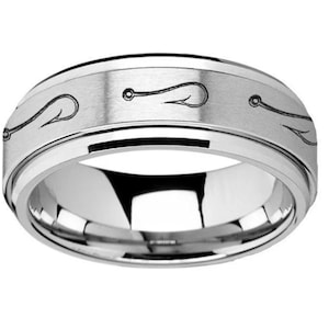 May include: A silver wedding band with a brushed finish and an engraved design of fishing hooks.