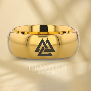Może przedstawiać: Złoty pierścionek z węglika wolframu z wygrawerowanym na górze czarnym symbolem węzła Val.