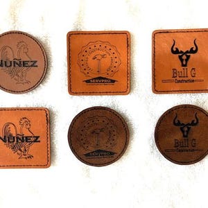 May include: Six leather coasters with different designs. Two coasters feature a rooster with the text "Nunez". Two coasters feature a bull with the text "Bull G Construction". Two coasters feature a hammer and the text "Servpro Certified Construction Services".