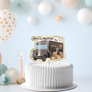 May include: A white frosted cake with a decorative topper showing a brown delivery truck with the words "Special Delivery Arriving Soon". The topper has a gold border. A lit candle is next to the cake. The cake is on a white cake board.