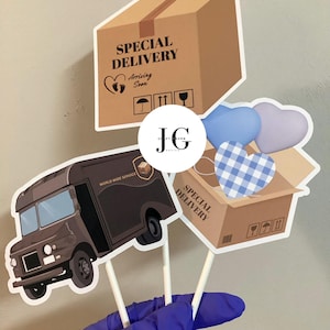 May include: Decorative cardboard cutouts on sticks, including a brown delivery truck, a box with "Special Delivery" text, and heart-shaped accents. The box has the text "Arriving Soon".