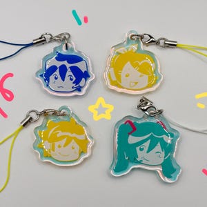 May include: Four acrylic charms with cartoon character faces. Each charm has a different character with blue, yellow, and teal hair. The charms are attached to silver-colored clasps with colored lanyards.