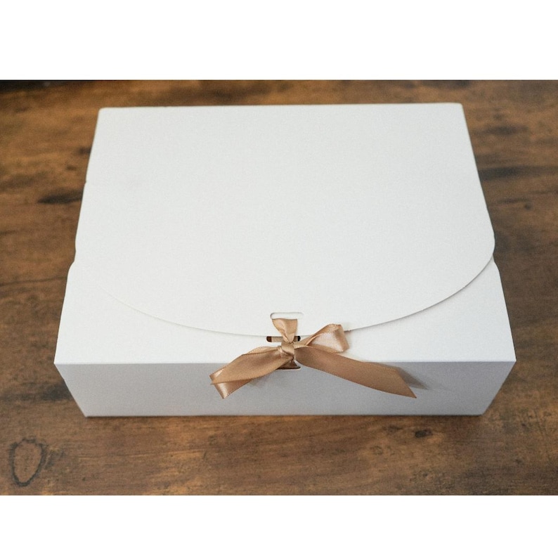 May include: A white gift box with a brown satin ribbon tied in a bow.