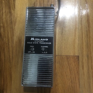 May include: A silver Midland 100 milliwatt solid state transceiver with a call button and channel selector. The buttons are labeled "Off - On" and "1, 2, 3".