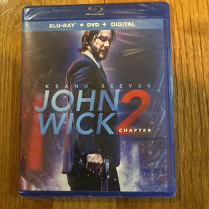 Puede incluir: Una copia en Blu-ray, DVD y digital de la película John Wick: Capítulo 2 protagonizada por Keanu Reeves. La portada presenta un primer plano de Keanu Reeves sosteniendo un arma.