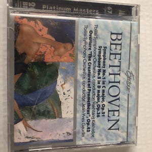 May include: A CD case with the name "BEETHOVEN" prominently displayed. The artwork on the cover is a painting with orange, blue, and white tones. The text details the symphony numbers, orchestra, and conductor.