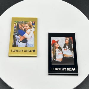 May include: Two rectangular photo magnets. One is gold with a photo of two women hugging, text reads "I LOVE MY LITTLE". The other is black with a photo of two women, text reads "I LOVE MY BIG".