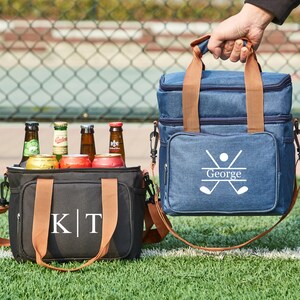 May include: Two personalized insulated cooler bags. One is black with brown straps and the initials "K|T" embroidered on the front. The other is blue with brown straps and the name "George" and a golf club design embroidered on the front.