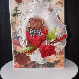 Tarjeta de lujo en 3D para el día de San Valentín para esposa, prometida y novia con un tierno osito de peluche y flores artificiales