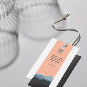 May include: A peach-colored tag with a white border and a mountain landscape illustration. The tag features the Arabic word "ال" and the text "Knowledge is light, and Rilah Al-Alim is the source of all wisdom-unseen and seen knowledge."