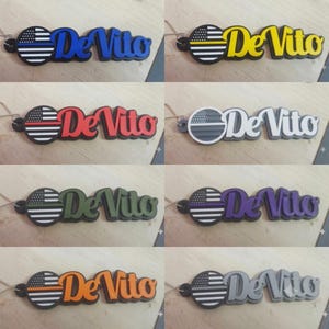 May include: A collection of eight custom keychains featuring a circular American flag emblem with a single horizontal colored stripe and the name "DeVito" in raised lettering. The colors include blue, yellow, red, white, green, purple, orange, and gray.