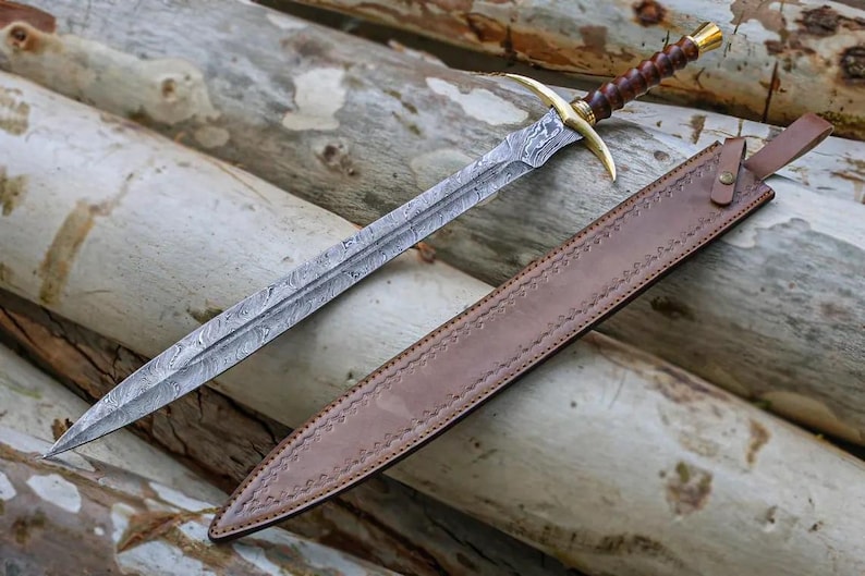 May include: A sword with a brown leather scabbard and a damascus steel blade. The sword has a gold-colored hilt and a brown wooden handle.