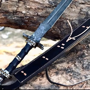 May include: A black leather scabbard with a decorative stitch pattern and a black and silver sword with a wooden handle. The sword has a Damascus steel blade with a decorative pattern.