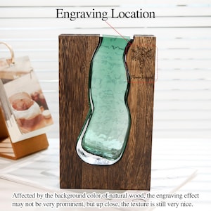 May include: A wooden vase with a clear, green glass insert. The vase has a dark brown wood frame and a floral engraving that reads "Flower Bouquet". The text "Engraving Location" is above the vase.