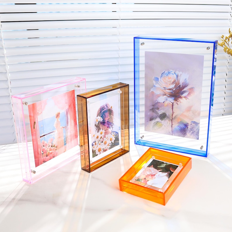 Pode incluir: Uma cole&ccedil;&atilde;o de molduras de fotos de acr&iacute;lico transparente em v&aacute;rias cores: rosa, &acirc;mbar, azul e laranja. Cada moldura cont&eacute;m uma imagem diferente, incluindo estampas florais e retratos. As molduras s&atilde;o retangulares e t&ecirc;m um design moderno e minimalista.