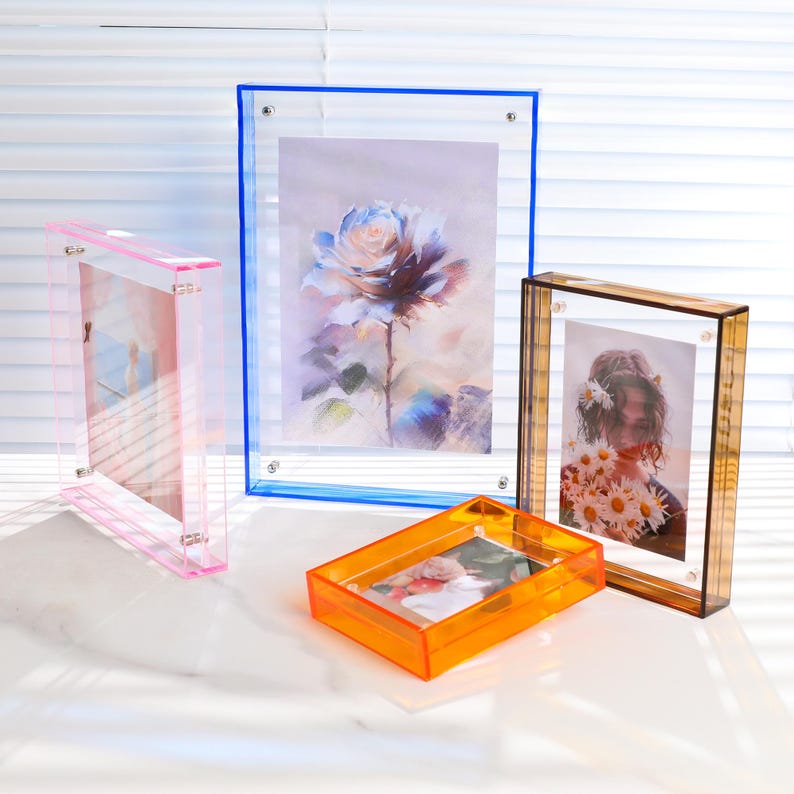 Pode incluir: Uma cole&ccedil;&atilde;o de molduras de fotos de acr&iacute;lico em v&aacute;rias cores e tamanhos. As molduras incluem rosa, azul, laranja e &acirc;mbar. Cada moldura cont&eacute;m uma imagem diferente, incluindo uma rosa em aquarela e um retrato de uma pessoa segurando flores.