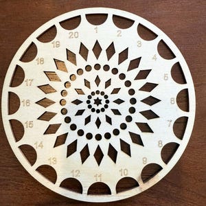 Może przedstawiać: Drewniane koło z spiralnym wzorem diamentów i kół. Koło jest ponumerowane od 1 do 20 wokół krawędzi.