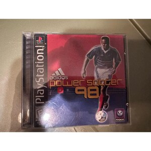 Może przedstawiać: Etui na grę wideo na PlayStation Adidas Power Soccer 98. Okładka przedstawia piłkarza w ciemnej koszulce i białych spodenkach, logo Adidas, tytuł oraz logo Psygnosis na tle z czerwono-niebieskim gradientem.