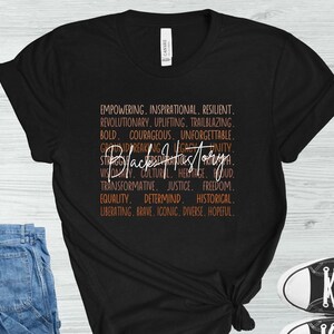 May include: Black t-shirt with the words "Black History" in a stylized font. The shirt features a list of empowering words in a contrasting color, including "Empowering," "Inspirational," and "Resilient."