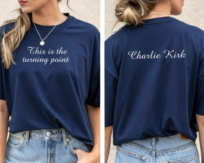 May include: Navy blue t-shirt with the text "This is the turning point" on the front and "Charlie Kirk" on the back. The shirt is a solid color and has a classic crew neck design. The shirt is paired with blue jeans.
