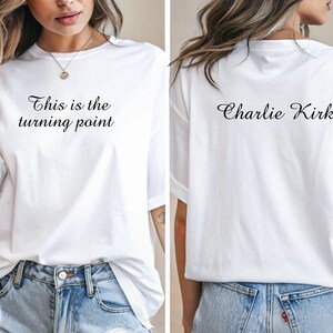 May include: White t-shirt with the text "This is the turning point" on the front and "Charlie Kirk" on the back. The shirt is a casual style, suitable for everyday wear.