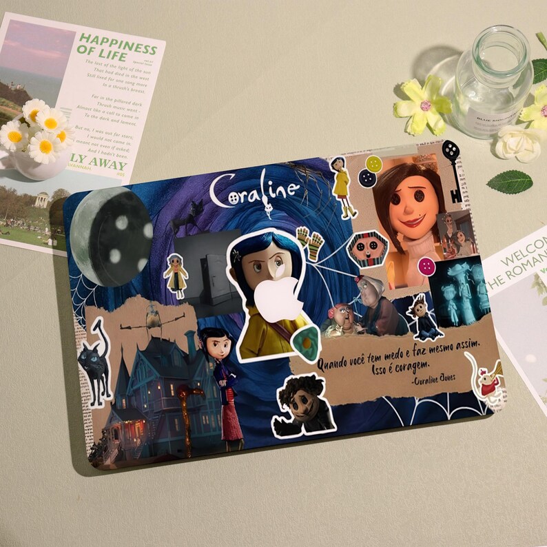 May include: A laptop case featuring a collage of images and text from the movie "Coraline." The design includes illustrations of characters, a moon, and the film's title. The case is decorated with stickers and a quote.