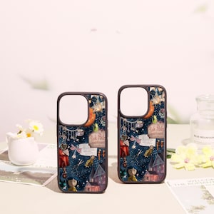 May include: Two dark-rimmed phone cases featuring a dark blue background with a whimsical collage of illustrations including a house, a character with blue hair, a sign reading Pink Palace apartments, stars, scissors, and various small trinkets.