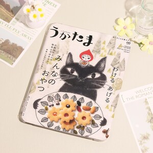 May include: A decorative tin featuring a black cat illustration with a red-hooded figure. The tin holds cookies and nuts on a plate. Japanese text is visible on the tin, along with the words "Happiness" and "Fly Away".