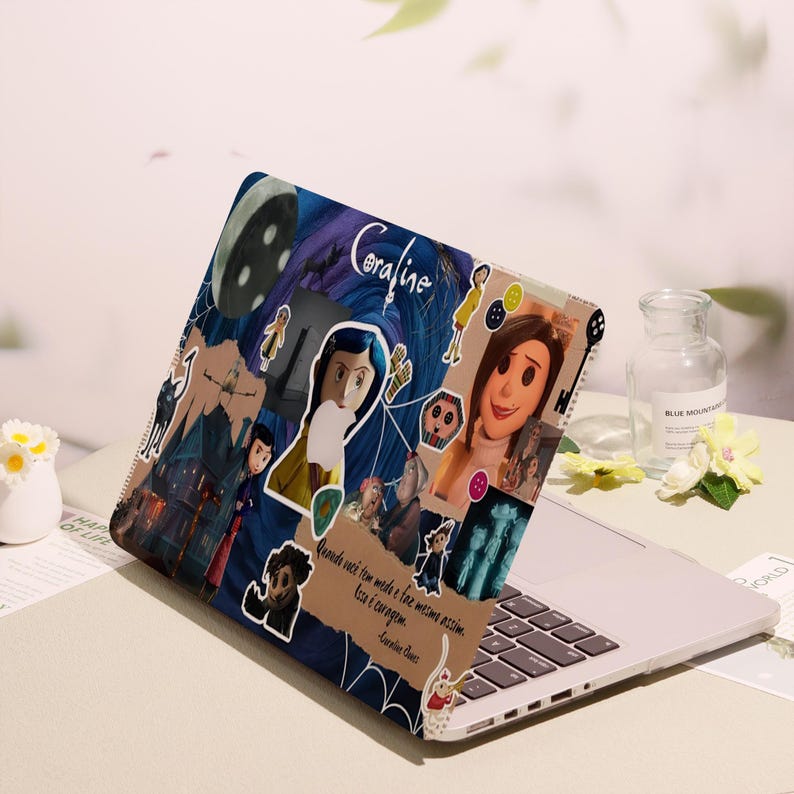 May include: Laptop case featuring a collage of images and text from the animated film "Coraline." The design includes illustrations of characters, a dark blue and purple background, and the film's title. The case is on a laptop.