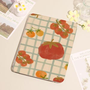 May include: A clear tablet case featuring a whimsical tomato pattern. The design includes large red tomatoes and smaller orange tomatoes, set against a light green and white checkered background. The case is a protective accessory for a tablet.