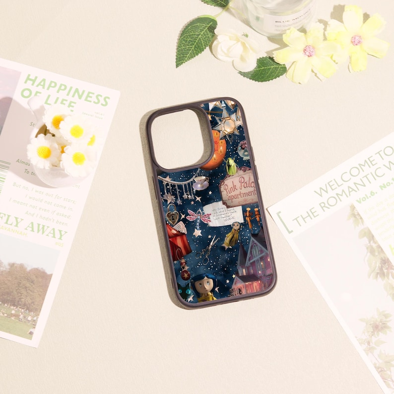 May include: A dark-colored smartphone case featuring a collage of various illustrated elements including a character with blue hair, a sign reading Pink Palace apartments, a key, a dragonfly, stars, and a house against a deep blue starry background.