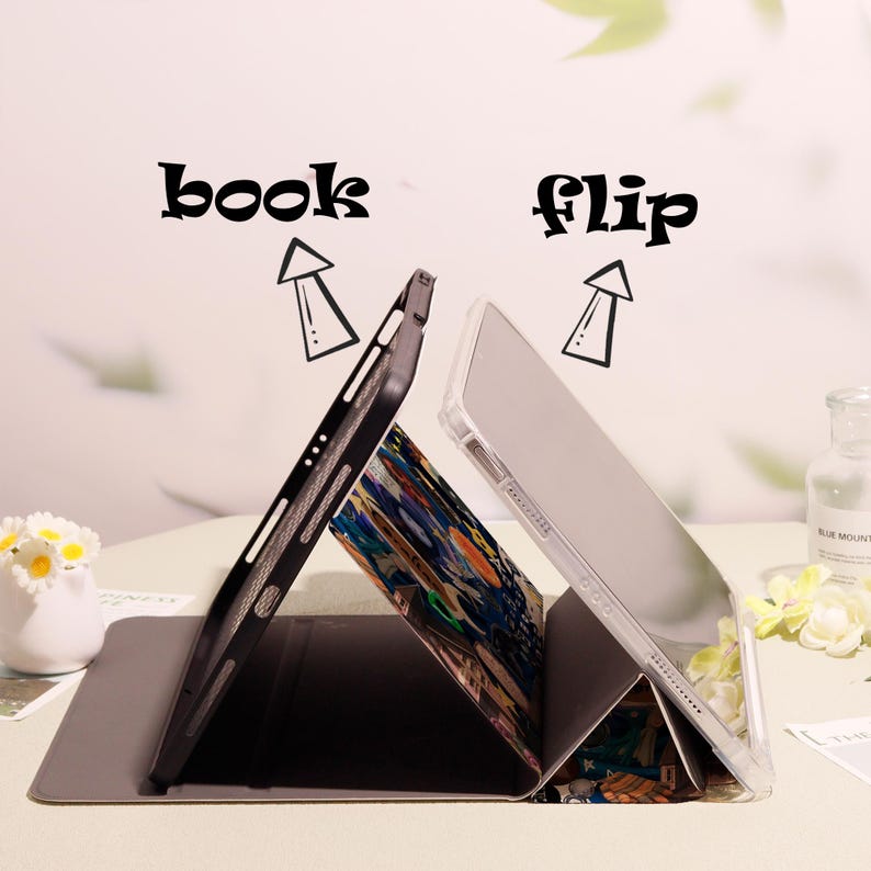 May include: Two tablet cases, one black and one clear, propped open to display the interior design. The cases are on a gray surface. The words "book" and "flip" are above the cases.