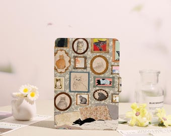 May include: A cat-themed tablet case featuring a collage of framed cat portraits in various styles and colors. The case includes a black cat resting on a patterned surface, with a floral background.
