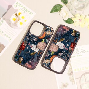 May include: Two dark-rimmed phone cases featuring a dark blue starry night background with various illustrated elements including a house, a sign reading Pink Palace apartment, a small doll figure, scissors, and a key against a starry sky.