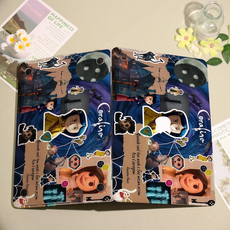 May include: Two tablet cases featuring a collage of images and text from the movie "Coraline." The cases have a dark blue and purple background with character stickers, a spider web design, and the word "Coraline."