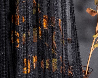 May include: Black sheer curtain with a textured, vertical stripe pattern. The curtain partially obscures a vase with dried leaves and branches. The curtain's weave allows glimpses of the objects behind it.