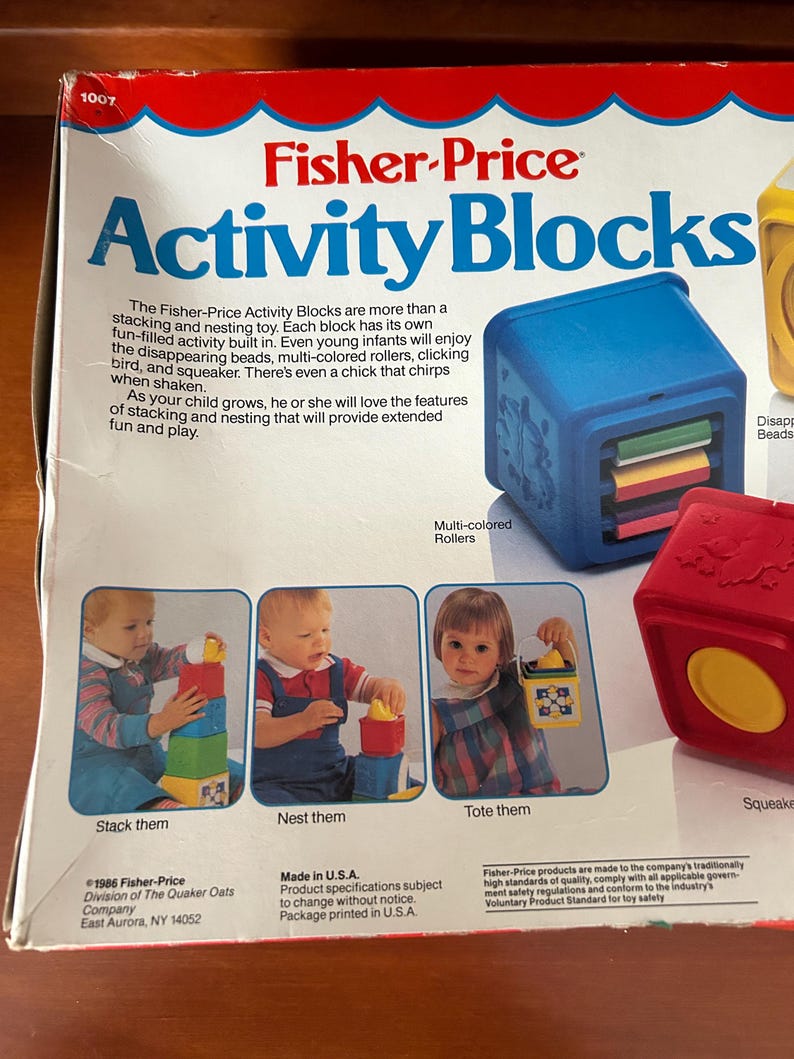 May include: A Fisher-Price Activity Blocks box, featuring the product name in blue. The box shows images of children playing with the blocks. Text describes the toy's features, including stacking and nesting capabilities.