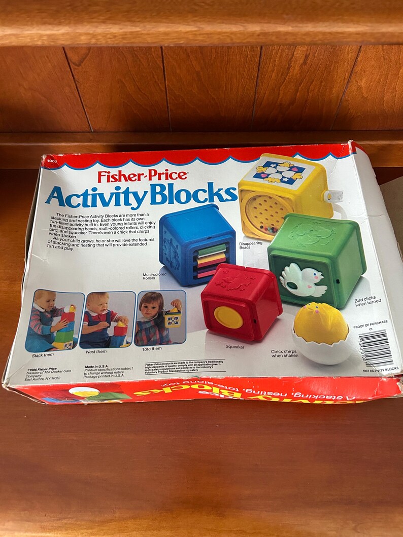 May include: Fisher-Price Activity Blocks toy set. The box features colourful blocks with various interactive elements. Includes a yellow block with disappearing beads, a red squeaker block, and a green block with a bird that clicks when turned.