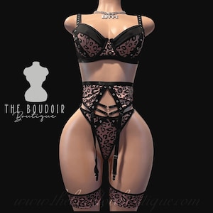 May include: A black and pink leopard print lingerie set with a bra, garter belt, and stockings. The bra has black straps and a black band around the bust. The garter belt has black straps and a black band around the waist. The stockings have a black band around the top and a leopard print pattern.