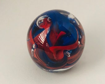 Blue and red glass has been swirled in a clear hand sculpted glass paperweight.