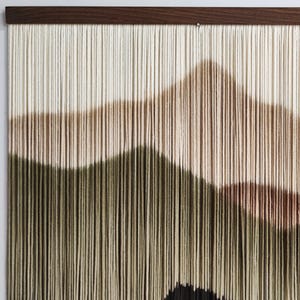 May include: A wall hanging made of yarn with a geometric design in shades of beige, brown, and green. The yarn is woven in a way that creates a textured, three-dimensional effect.