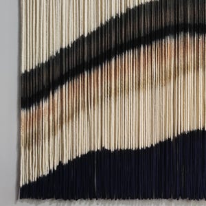 Peut inclure: Une tapisserie murale en fil avec un motif g&eacute;om&eacute;trique de rayures noires, blanches et brunes. Le fil est tiss&eacute; de mani&egrave;re &agrave; cr&eacute;er un effet textur&eacute; et tridimensionnel.