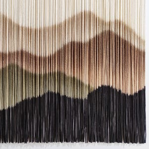 May include: A wall hanging made of yarn with a wavy pattern in shades of brown, green, and black.